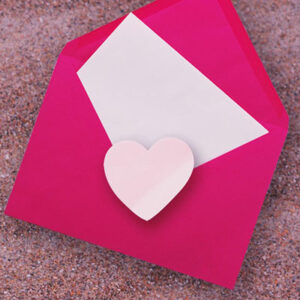 Red envelope with heart and note. Writing a unique wedding anniversary greeting message.