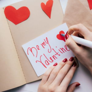 What to write in a card for valentines day. Be my valentine writing in a valentines card with red pen and red love hearts.
