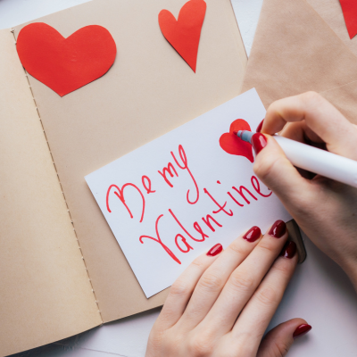 What to write in a card for valentines day. Be my valentine writing in a valentines card with red pen and red love hearts.
